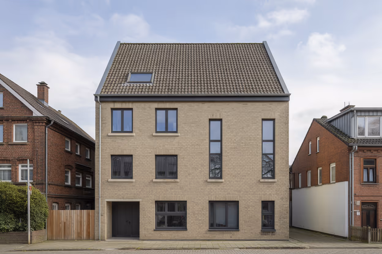modernes dreist ckiges wohnhaus mit beiger backsteinfassade und mehreren fenster
